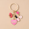 Gold-toned enamel heart keychain with a pink liquid bottle charm and an XOXO heart charm