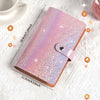 Un cahier rose pailleté avec une couverture en cuir est montré sur une surface blanche.
