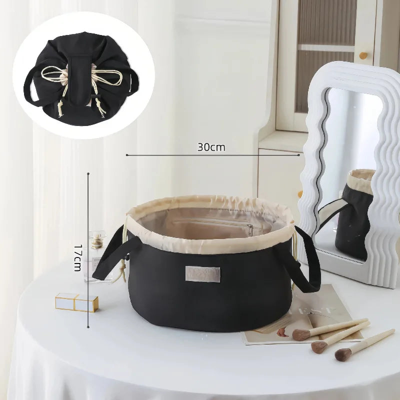 Black instant-open flat lay makeup organizer bag with a drawstring closure displayed on a white table.