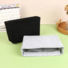 A black felt cosmetic bag insert organizer next to a light gray felt pouch on a green surface.