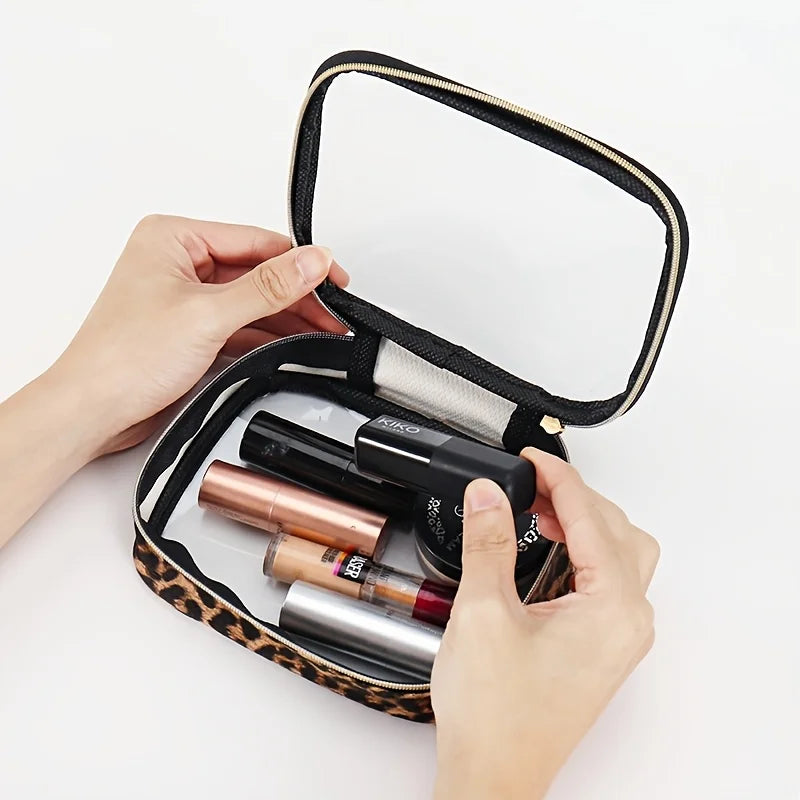 A hand holds a leopard print clear cosmetic bag with a black strap, showing various makeup products inside.