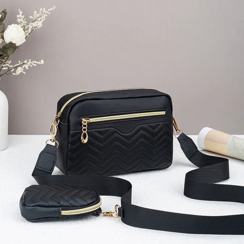 Schwarze gesteppte Crossbody-Tasche mit goldfarbenen Beschlägen auf weißem Untergrund.
