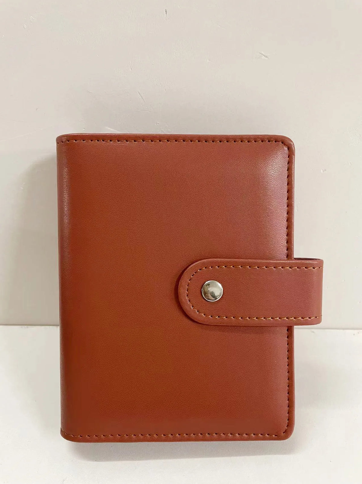 A brown leather ring binder notebook with a stitched cover and silver clasp.