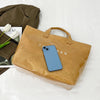 Un smartphone azul claro dentro de una bolsa de papel marrón sobre una superficie blanca.