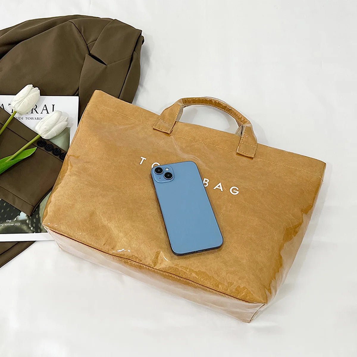 Un smartphone azul claro dentro de una bolsa de papel marrón sobre una superficie blanca.