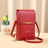 A red leather women's touch screen crossbody shoulder bag with gold hardware resting on a light wooden surface.