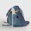 Bolso cruz de nylon azul claro con correa beige y ribete blanco contra fondo blanco.