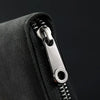 Close-up of a black card wallet showing a silver zipper and an RFID blocking card slot.
