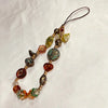 A delicate beaded phone charm strap with various colored stones and a thin cord.