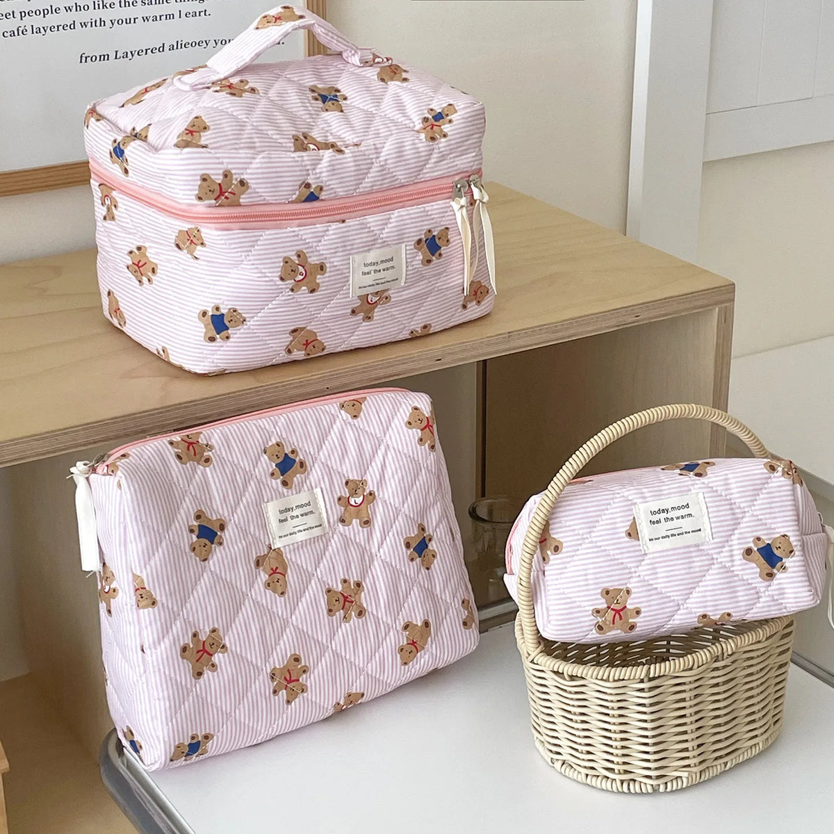 A pink and white striped bear cosmetic makeup bag is shown resting on a wooden surface.