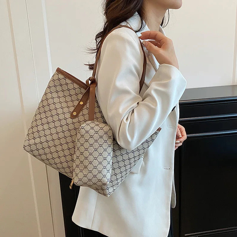 A woman holds a beige geometric patterned tote bag with brown leather trim against a white background.