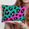 Une main tient une pochette de maquillage à imprimé léopard teal et magenta vibrants.