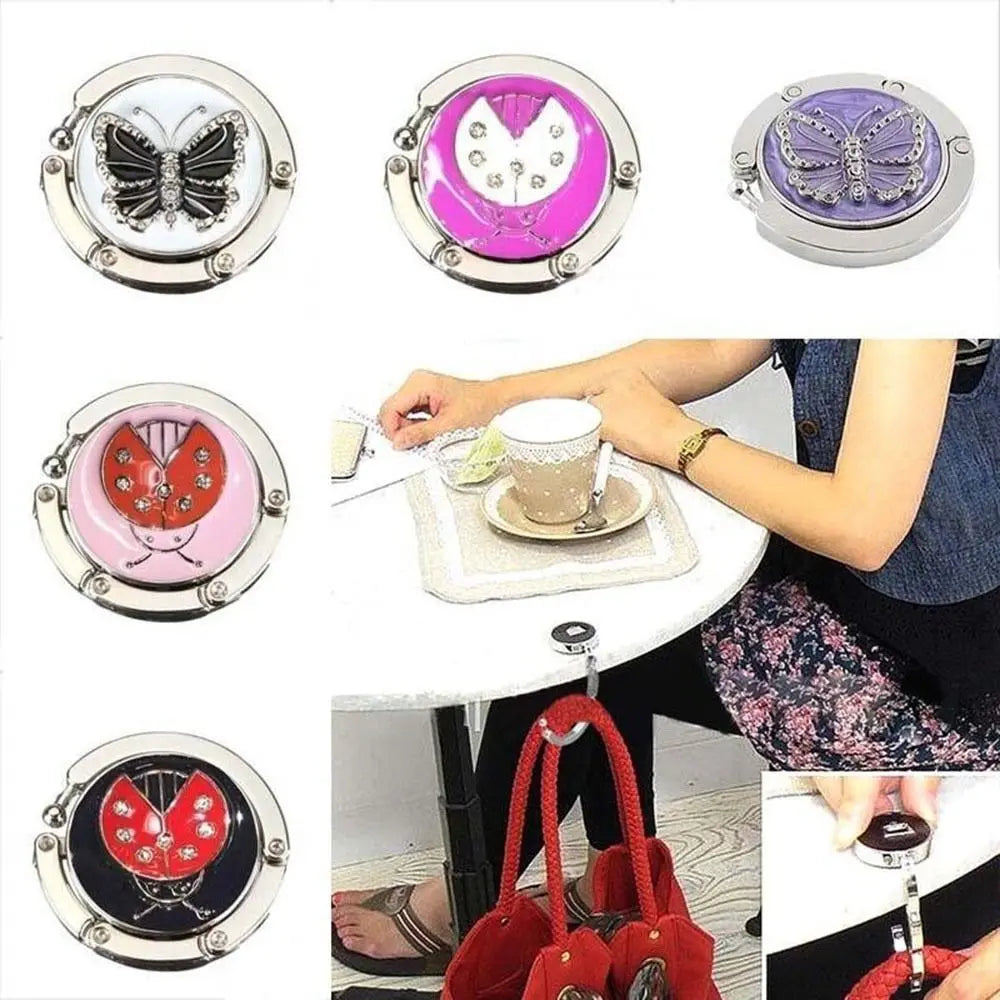 Varias vistas de un gancho de soporte para mesa mariposa plegable de aluminio en colores plateado y rosa.