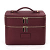 A maroon double-layer makeup storage case with gold zipper pulls and a leather finish.