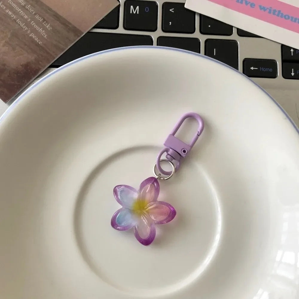 A purple and yellow resin flower keychain rests on a white ceramic plate.