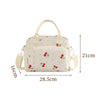 A cream-colored floral corduroy insulated lunch bag with light green and red fruit patterns.