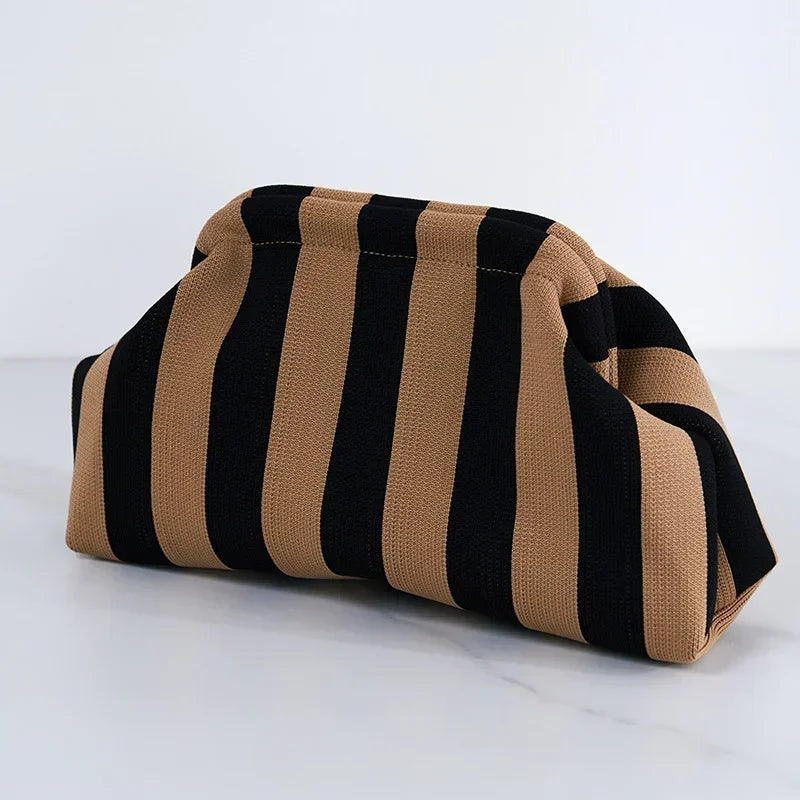 A beige and black striped summer crochet handbag is shown lying on a white surface.