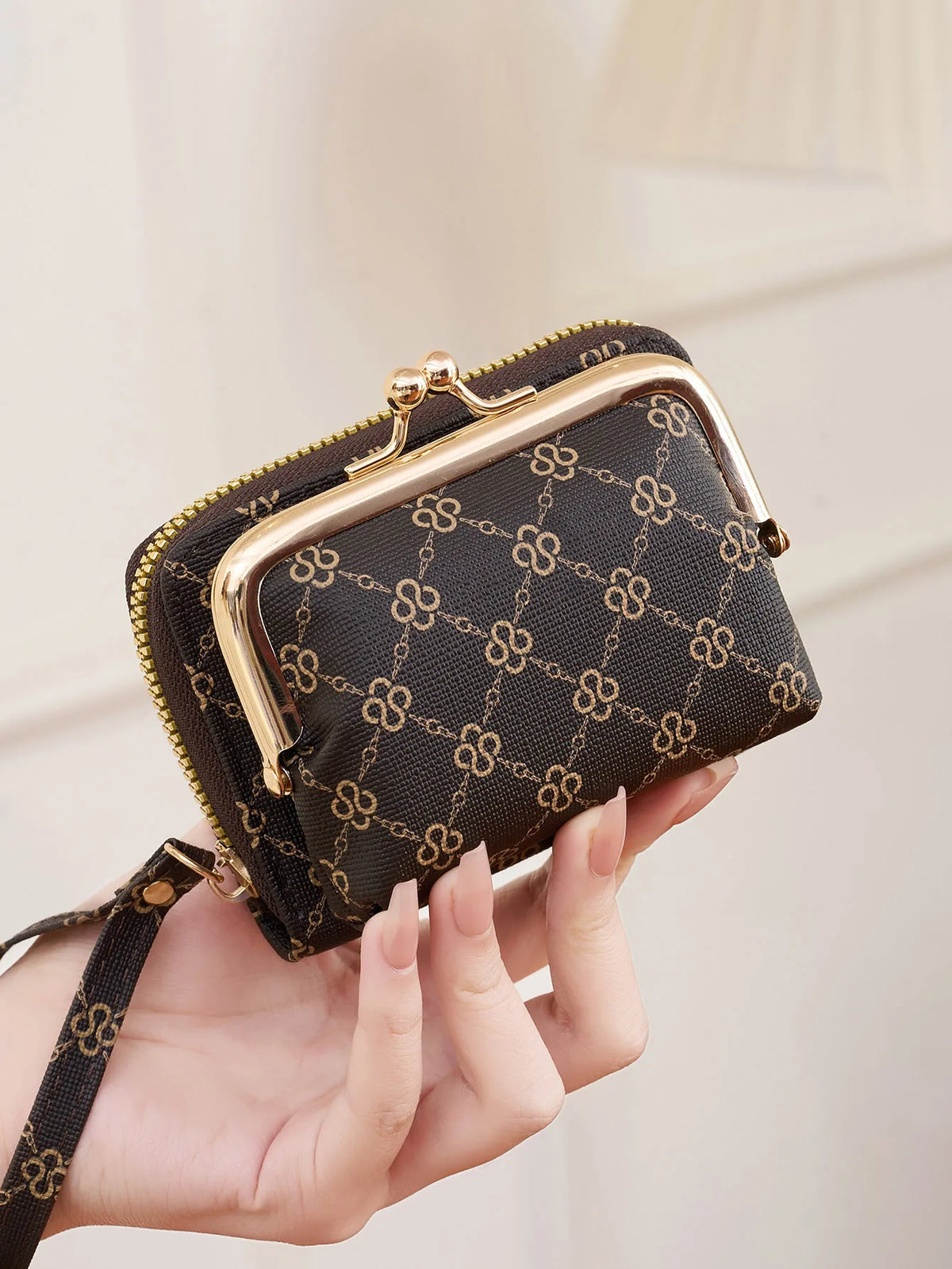 A hand holds a black quilted fashion print accordion card holder wallet with gold hardware.