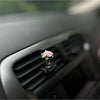 Eine kleine rosa Rose in einer Glasvase auf dem Armaturenbrett und in einem Auto-Lüftungsschlitz
