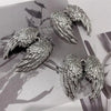 Silver metal angel wing keychain charms displayed on a light background.