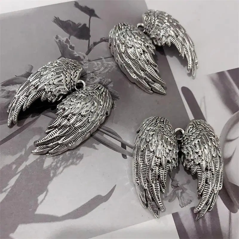 Silver metal angel wing keychain charms displayed on a light background.