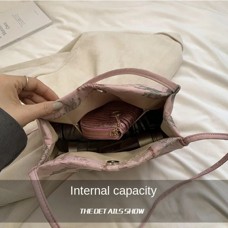 Bolso de seda jacquard rosa claro retro abierto, mostrando su forro interior sobre una superficie blanca.