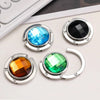 A collection of round acrylic foldable hooks in blue, black, and green set against a white background.