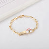 Gold chain bracelet with a rainbow heart charm on a white background.