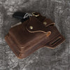 A brown genuine leather men's waist bag with a black leather strap and metal hardware resting on a gray textured surface.