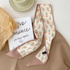 Foulard pour cheveux en soie beige avec motif floral orange, présenté sur fond neutre.