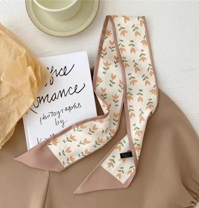 Foulard pour cheveux en soie beige avec motif floral orange, présenté sur fond neutre.