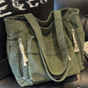 Sac cabas vert en velours côtelé avec plusieurs poches et sangles, exposé sur une surface sombre.