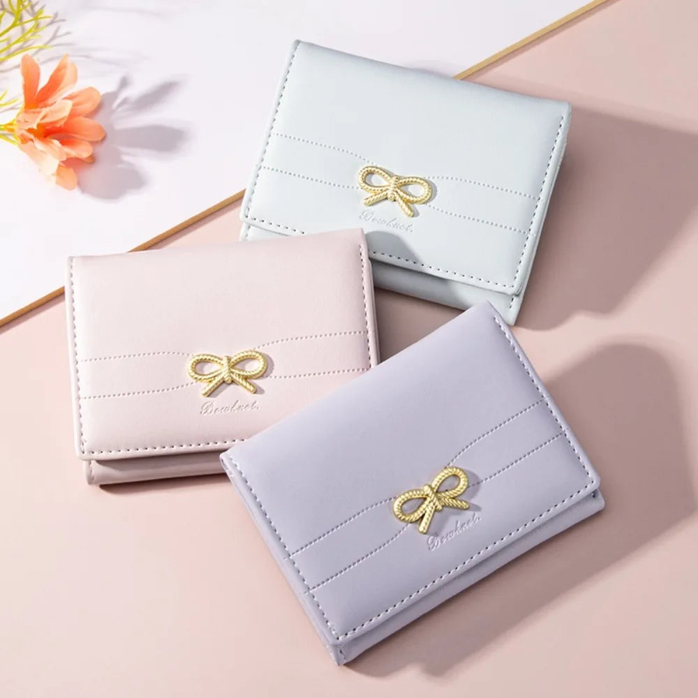 Un ensemble de trois porte-cartes pliants en PU rose pâle et lavande avec des ornements de nœud doré.