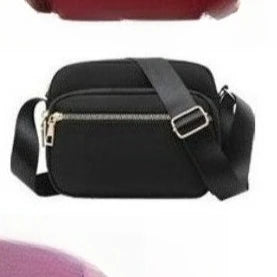 Black compact oxford fabric crossbody bag with a silver zipper and black strap