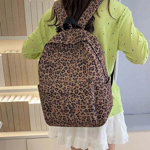 Une personne porte un sac à dos en nylon à imprimé léopard marron sur une veste vert lime et une jupe blanche.