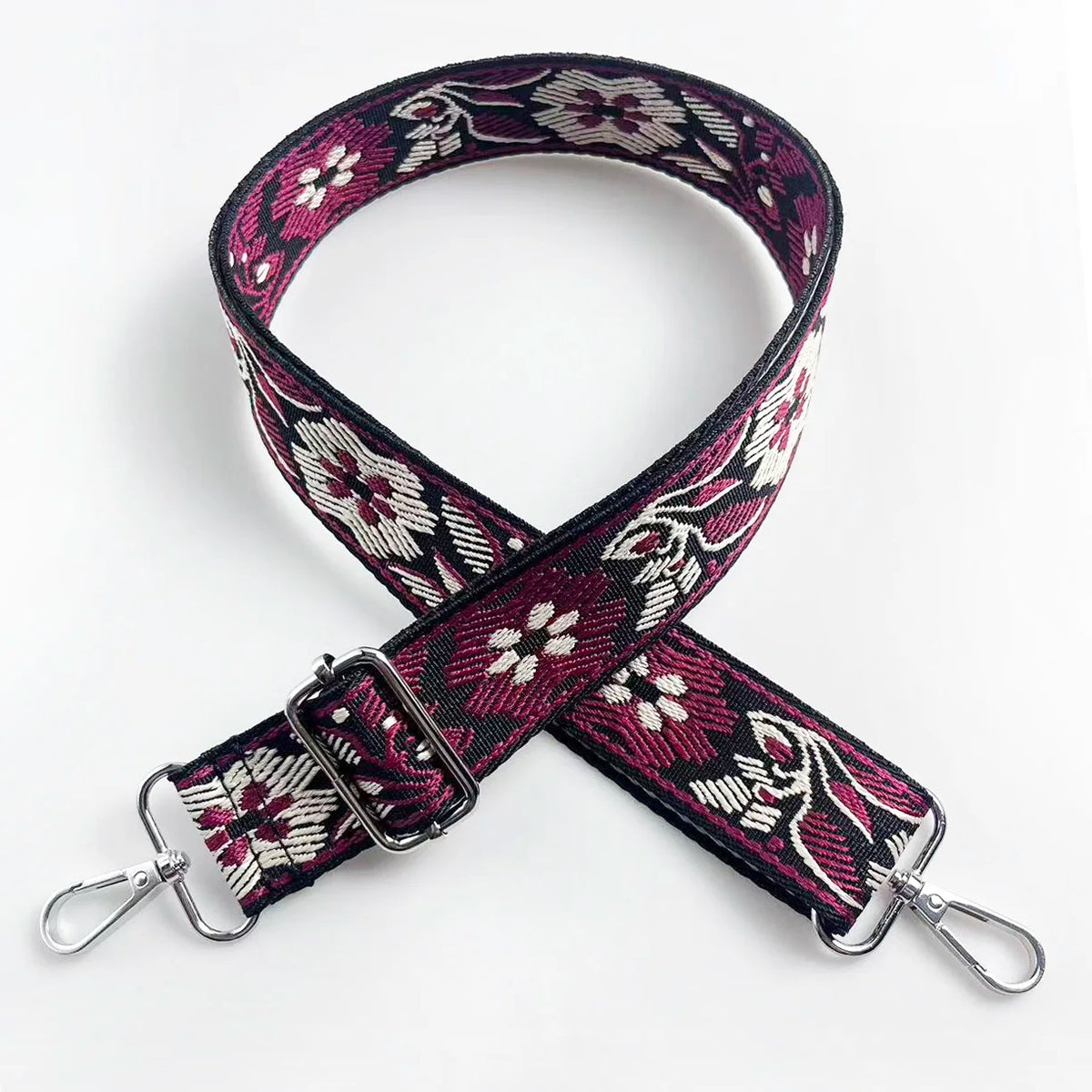 A patterned magenta and white floral jacquard strap for a crossbody bag.