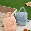 A pink and light blue double-layer insulated lunch bag displayed on a white surface with fruit.