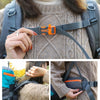 Une personne portant un pull marron ajuste une sangle orange sur un sac à dos d'escalade gris extérieur.