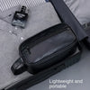A black leather travel cosmetic bag is shown resting on a gray fabric, next to a perfume bottle.