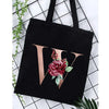 Black canvas tote bag featuring a gold letter V design with a deep red floral print.