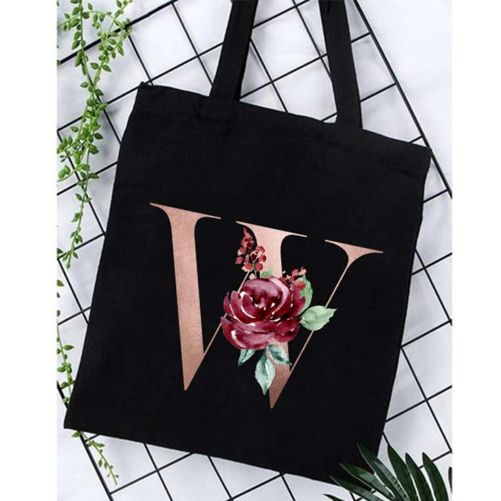 Black canvas tote bag featuring a gold letter V design with a deep red floral print.
