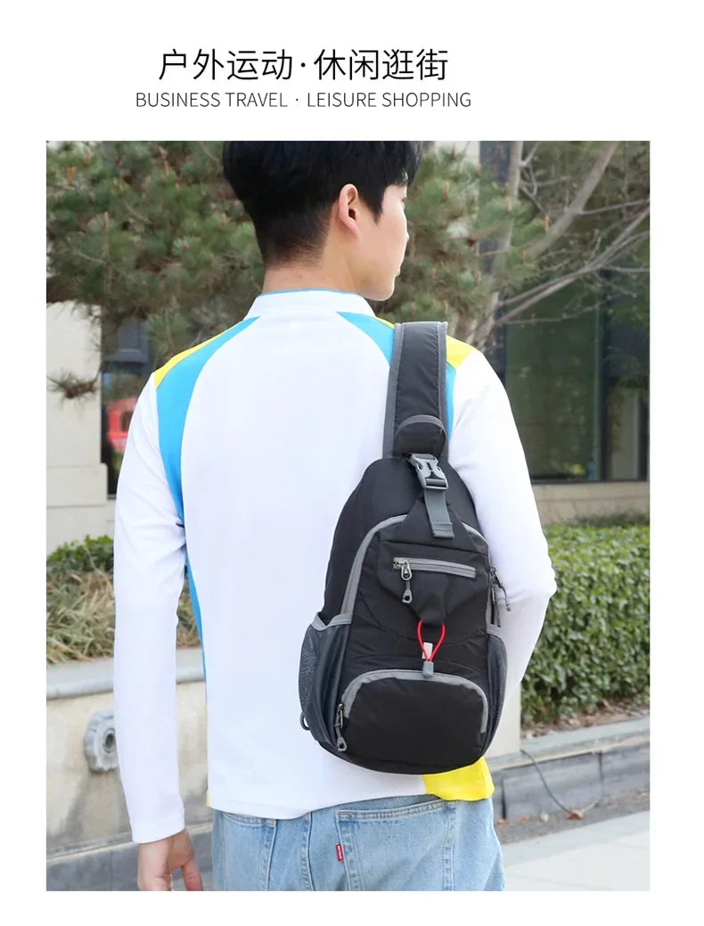 A man wearing a white shirt and jeans is carrying a black nylon chest sling bag outdoors.