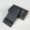 A black carbon fiber money clip is displayed in its box, showing the texture and branding.