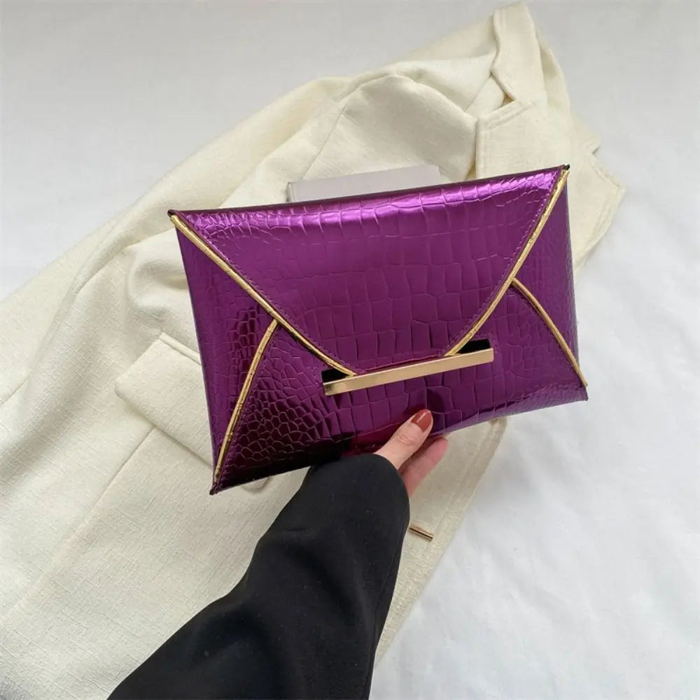 A purple crocodile pattern coin purse clutch is shown being held by a hand against a cream-colored jacket.