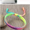 A close-up of a handmade braided rope bracelet featuring colorful threads in shades of green, blue, orange, and purple.
