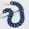 A dark blue matte acrylic chain necklace with a gold-colored clasp is displayed on a white background.