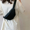 A woman wearing a white shirt carries a black nylon waist bag across her body.