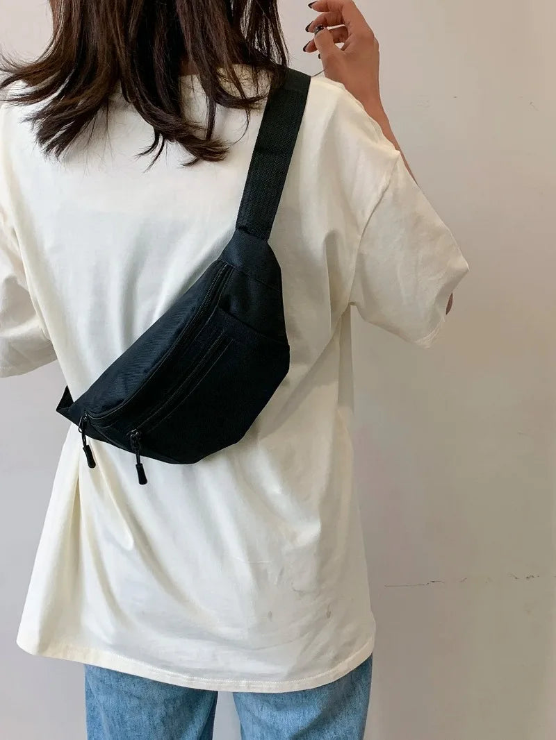 A woman wearing a white shirt carries a black nylon waist bag across her body.