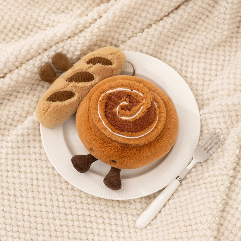 A pair of brown and orange cartoon character plush toys resting on a white plate on a cream knitted fabric.