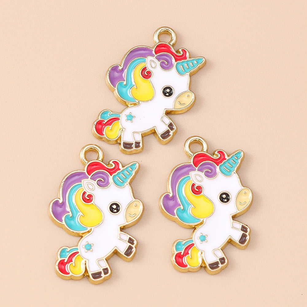 Two gold-toned unicorn horse charm pendants featuring rainbow colors and white enamel on a beige background.